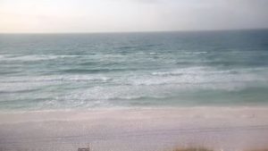 Live view from Destin Beach Cam showing the pristine shoreline and white sand dunes of Henderson Beach State Park under a clear blue sky