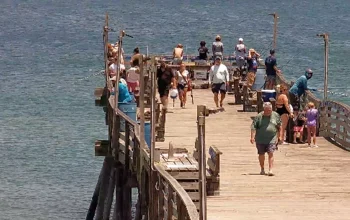 Scenic ocean view from Avalon Pier in Kill Devil Hills, NC, showing clear blue water, gentle waves, and a bright sky along the Outer Banks coast