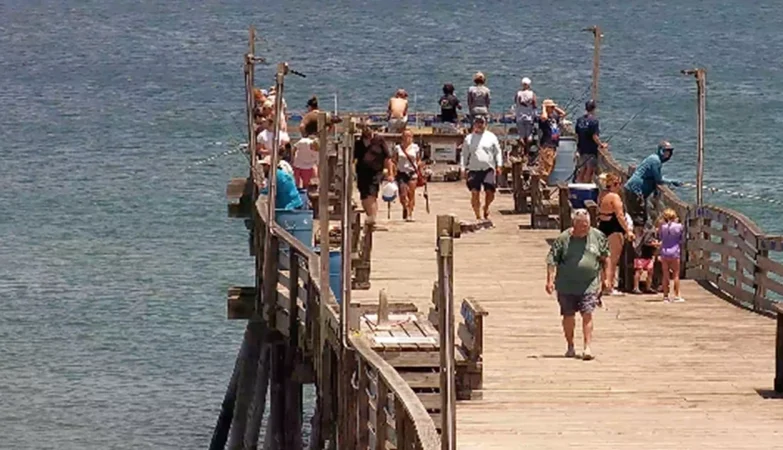 Scenic ocean view from Avalon Pier in Kill Devil Hills, NC, showing clear blue water, gentle waves, and a bright sky along the Outer Banks coast