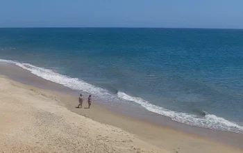 Live view of Buxton NC Beach showing gentle ocean waves, sandy shoreline, and clear skies along the Outer Banks coast