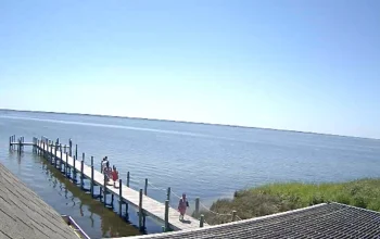 Live view of Duck, NC from Duck Boardwalk webcam showing coastal scenery, boardwalk path, and surrounding waterfront area.