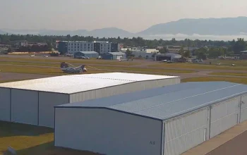 Bird’s eye view of Kalispell, Montana Airport showing runways, taxiways, aircraft, and surrounding mountainous landscape under clear skies.