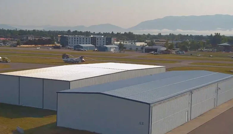 Bird’s eye view of Kalispell, Montana Airport showing runways, taxiways, aircraft, and surrounding mountainous landscape under clear skies.