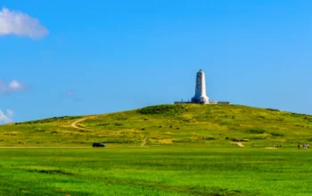 Scenic view of the Wright Brothers National Memorial in Kill Devil Hills, North Carolina, with the granite monument standing tall against a clear blue sky, commemorating the first powered flight.