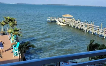 Scenic bayside waterfront view from Aloft Ocean City featuring calm waters, a gorgeous pier, and a vibrant sunny sky.
