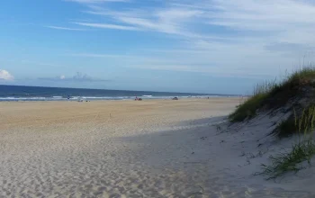 Scenic view of the Outer Banks coastline in North Carolina with sandy beaches, ocean waves, and blue skies.