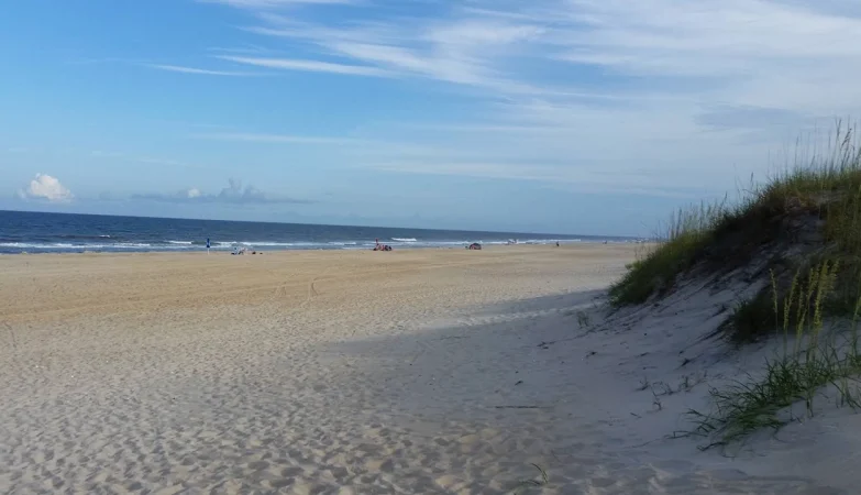 Scenic view of the Outer Banks coastline in North Carolina with sandy beaches, ocean waves, and blue skies.