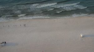Sweeping beach view from a Phoenix IX balcony in Orange Beach, Alabama, showing white sand, gentle waves, and the Gulf stretching to the horizon.
