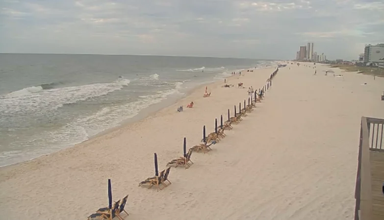 View of the Gulf of Mexico from Sea N Suds in Orange Beach, Alabama, with white sand beach, blue waves, and sunny sky.
