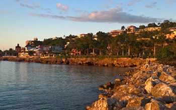 Live webcam view of Montego Bay, Jamaica, showing turquoise Caribbean waters, boats in the harbor, and palm-lined beaches with people enjoying the sun near the bustling coastal city.